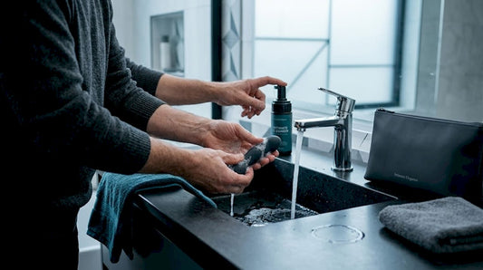 Person cleaning sex toy with soap in bathroom