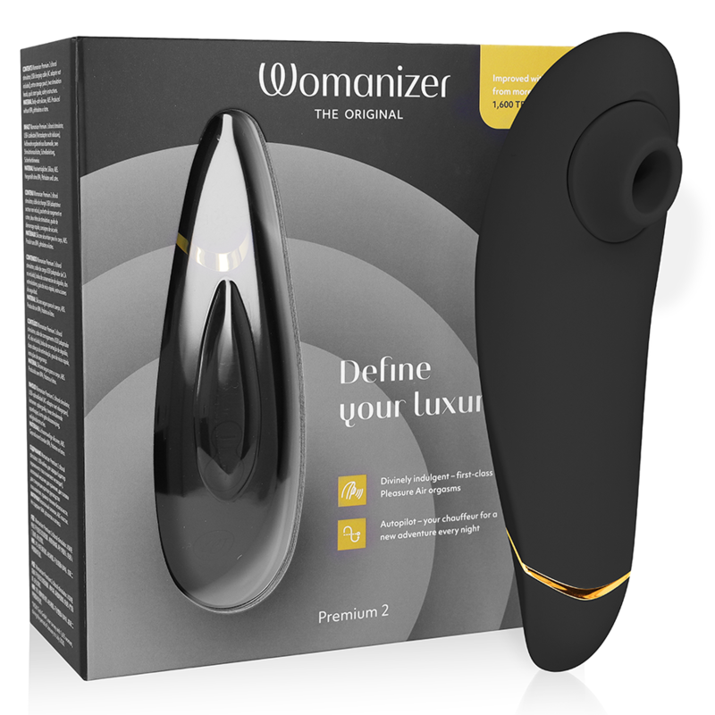 Black ergonomic clitoral stimulator with gold accent and silicone suction tip, next to product box.