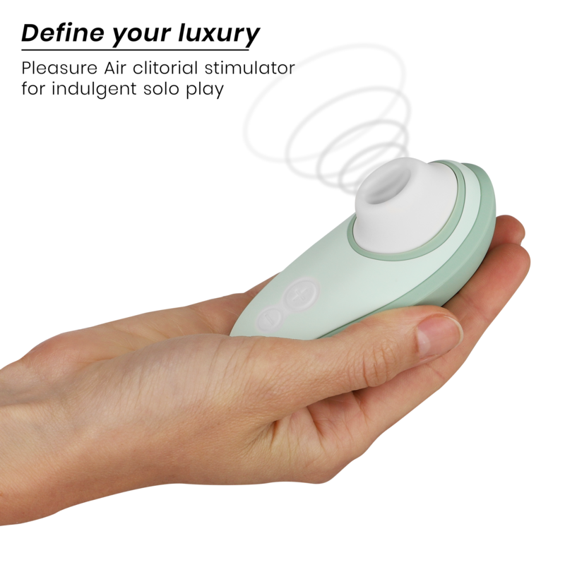 Light green Womanizer Liberty 2 clitoris stimulator with white suction tip held in hand.