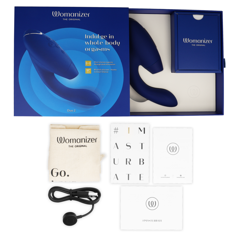 Blue Womanizer Duo 2 stimulator with curved dual ends, USB charging cable, white storage pouch, and instruction manuals in.