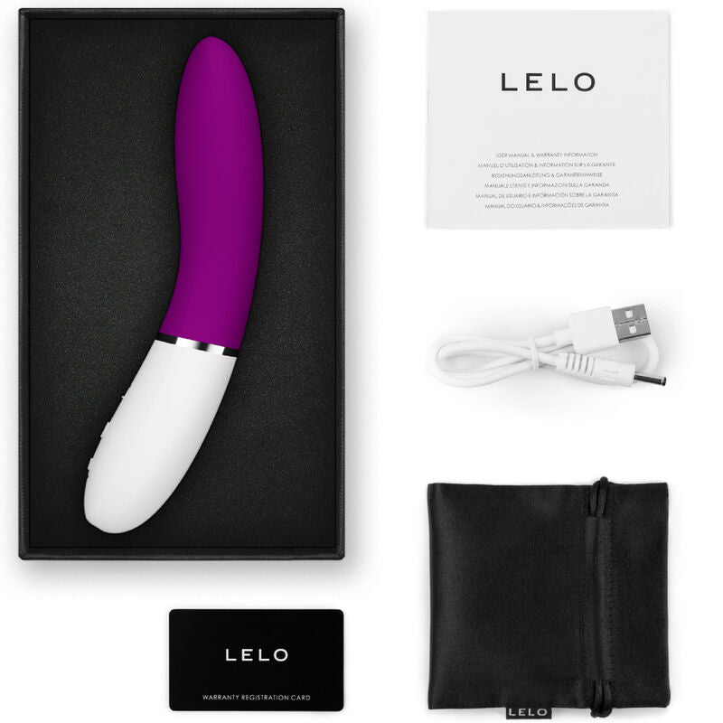 Purple and white curved G-spot stimulator with USB charging cable, black storage pouch, and instruction manual in black box.