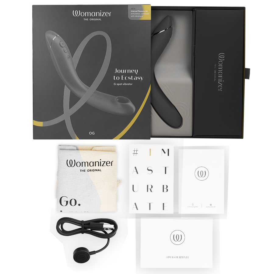 Slate gray Womanizer OG G-spot vibrator with ergonomic curved design, displayed with black box, USB cable, and user manuals.