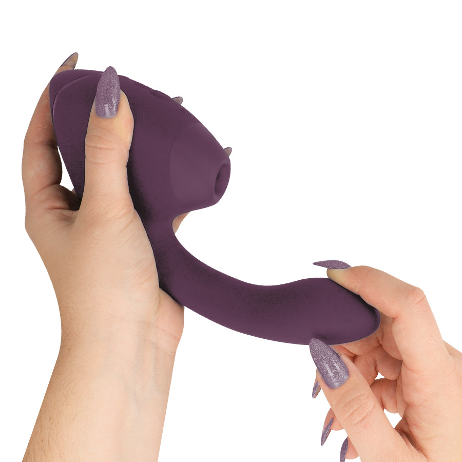 Dark purple dual clitoral and G-spot stimulator with curved, textured design held by hands with matching purple nails.