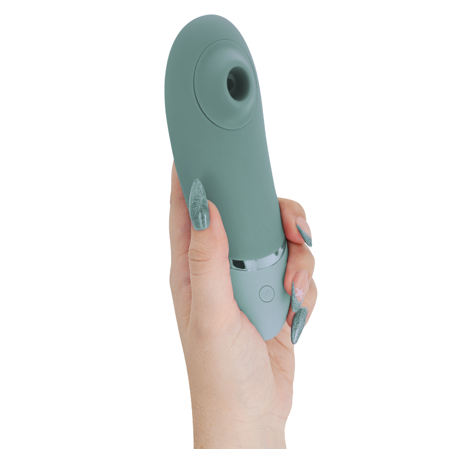 Sage green Womanizer Next clitoral stimulator held in hand with silver accent and button.